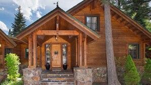 Una baita di legno con fondamenta in pietra, un portico in legno e un'ampia porta principale.