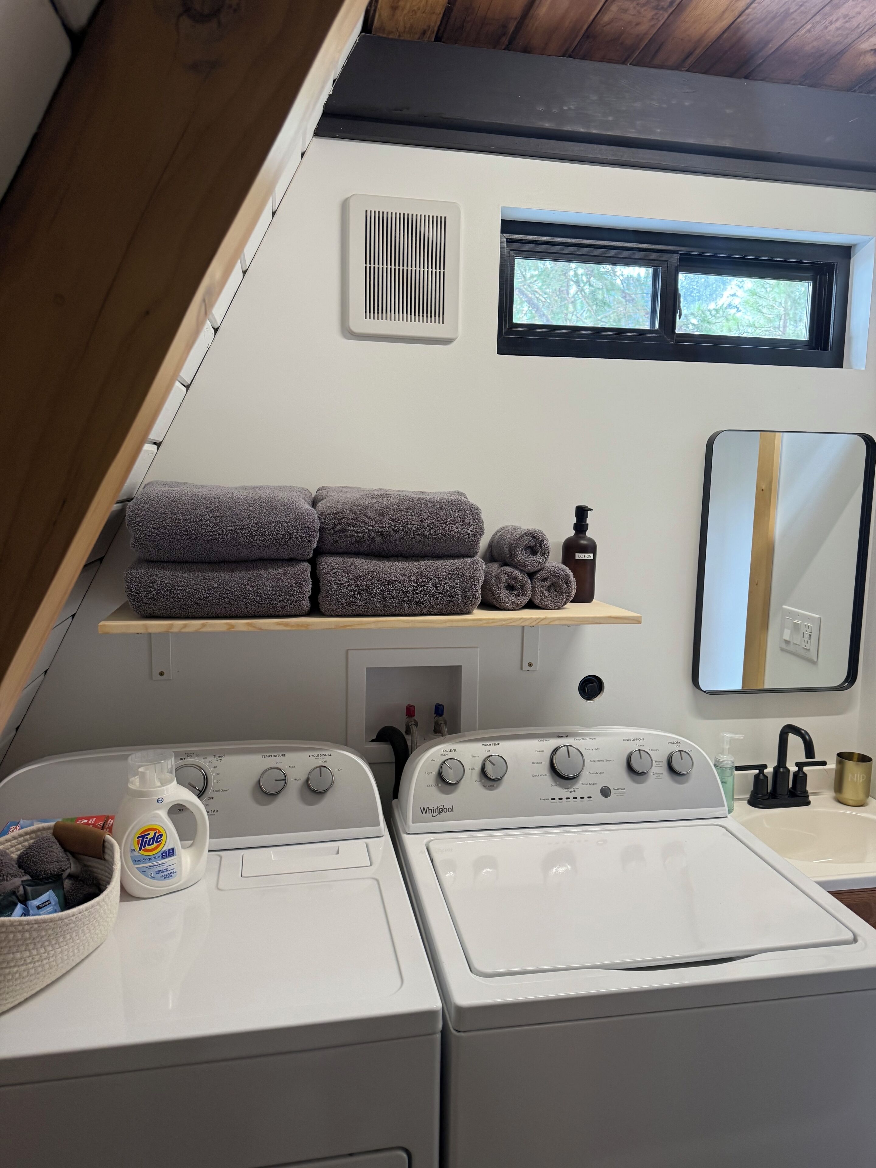 Un espace buanderie avec des piles de serviettes, une bouteille de lessive et deux sèche-linge Whirlpool.