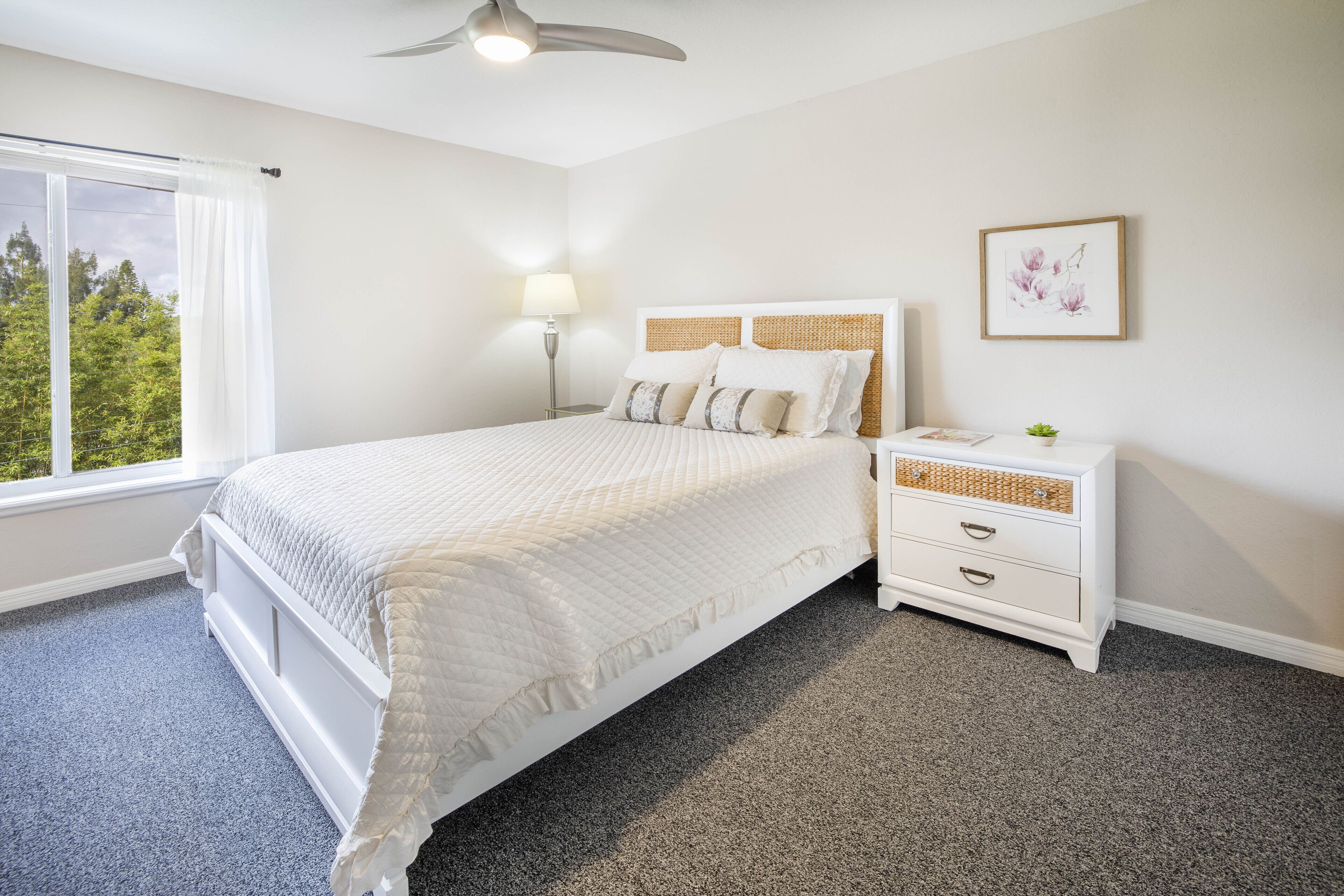 A bedroom with a bed, bedside table, lamp, and a framed picture on the wall.