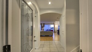 A hallway leading to a living area with a sofa, a coffee table, and a kitchen area in the background. - 5 STAR SIESTA KEY, 80 STEPS to BEACH, LUXURY POOL, 6 BEDROOMS, SPACIOUS LIVING (Siesta Key)