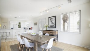 A modern kitchen with white cabinets, a wooden dining table, and white chairs. - 5 STAR SIESTA KEY, 80 STEPS to BEACH, LUXURY POOL, 6 BEDROOMS, SPACIOUS LIVING (Siesta Key)