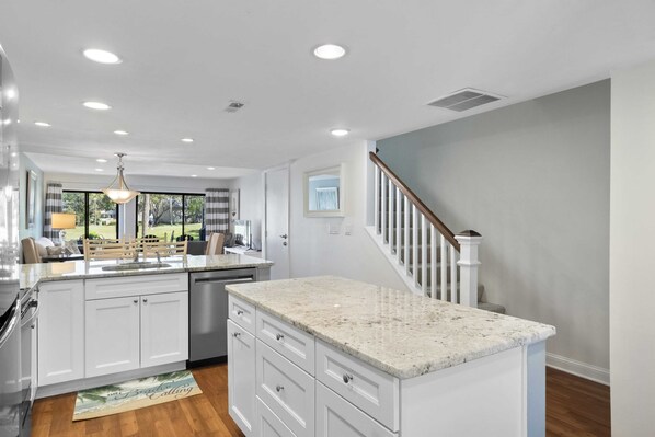 A modern kitchen with white cabinetry, granite countertops, and a central island.