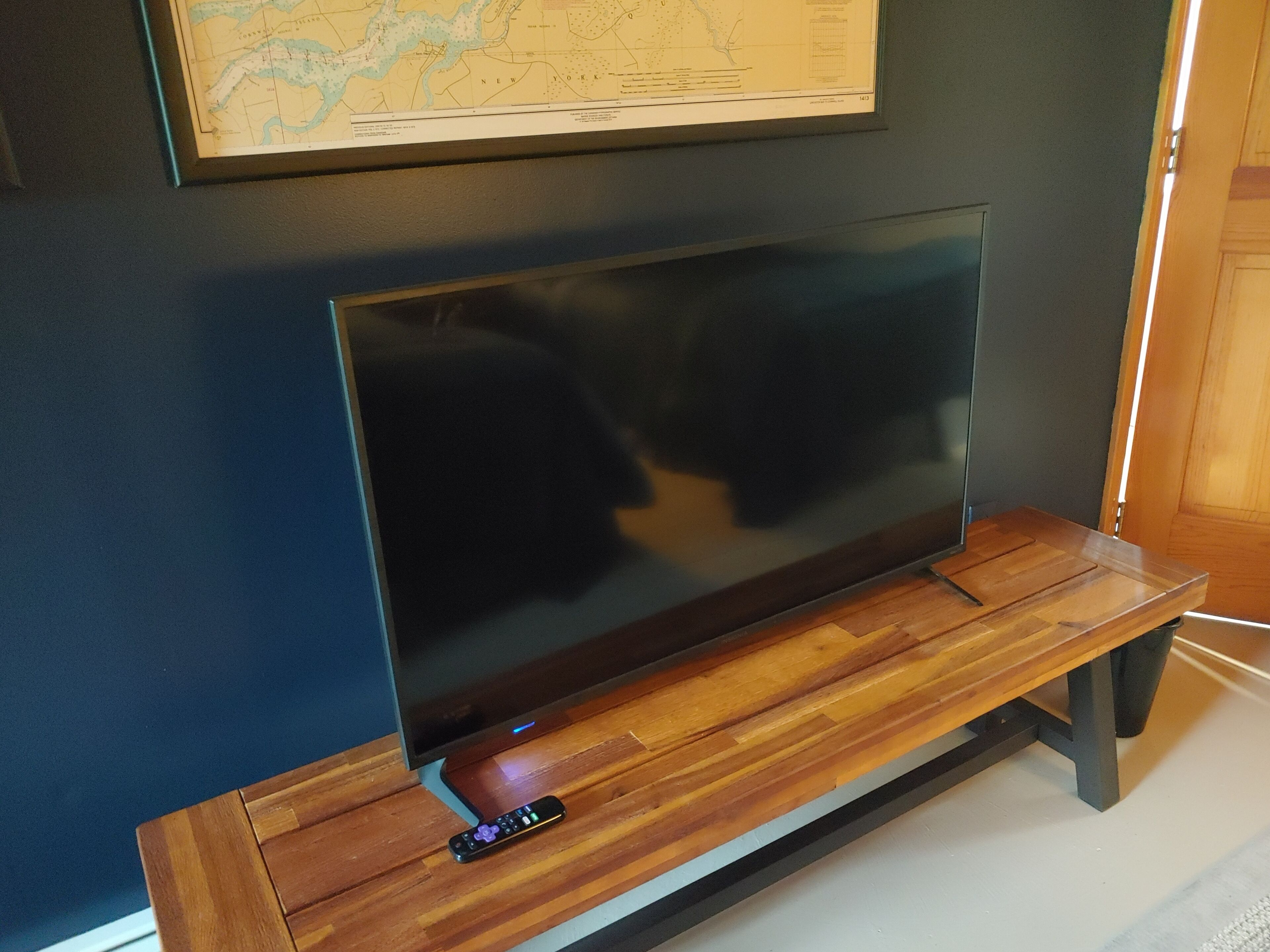 A flat-screen TV on a wooden stand with a remote control beside it.