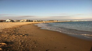 A beach with a sandy shore, a few scattered rocks, and a calm sea.