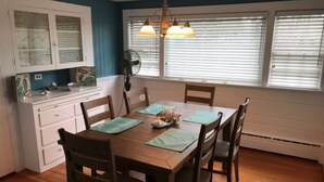 Une salle à manger avec une table en bois, six chaises et un lustre.