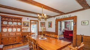 A dining room with a wooden table and chairs, a chandelier, and a wooden cabinet with dishes. - Mountain House Magic (Newry)