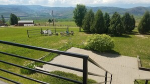 A grassy outdoor area with a paved path, a metal railing, and a view of distant mountains. - Come stay at the McMinn Inn and enjoy the mountian views! (Inkom)