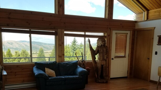A spacious room with a large window, a wooden ceiling, a blue sofa, and a statue. - Come stay at the McMinn Inn and enjoy the mountian views! (Inkom)
