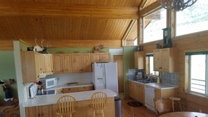 A wooden cabin-style kitchen with a central island, wooden cabinets, and a dining area with two chairs. - Come stay at the McMinn Inn and enjoy the mountian views! (Inkom)