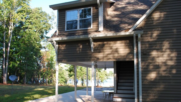 A two-story house with a covered patio, a front door, and a small outdoor seating area.