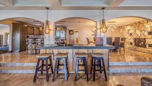 A spacious kitchen with a central island, bar stools, and hanging pendant lights.