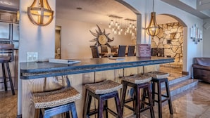 A modern kitchen with a central island, bar stools, and pendant lighting.