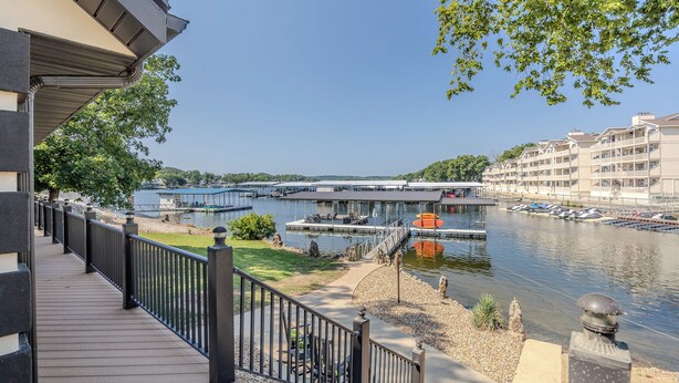 A waterfront view from a balcony with a wooden deck, a bridge, and a marina with boats.