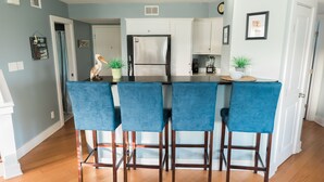 A modern kitchen with a central island, bar stools, and a refrigerator. - Always a great time on south island of Tybee! and short drive to Savannah! (Tybee Island)