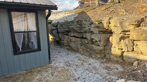 A rustic stone wall adjacent to a wooden building with a window.