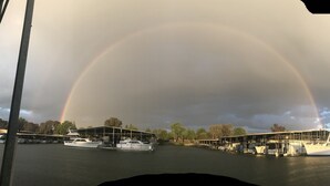 A marina with boats docked under a large rainbow.