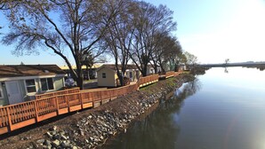 A row of single-story houses with a wooden fence along a calm water body.