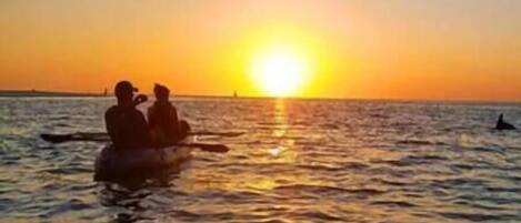 Un atardecer sobre una masa de agua con dos personas en un bote.