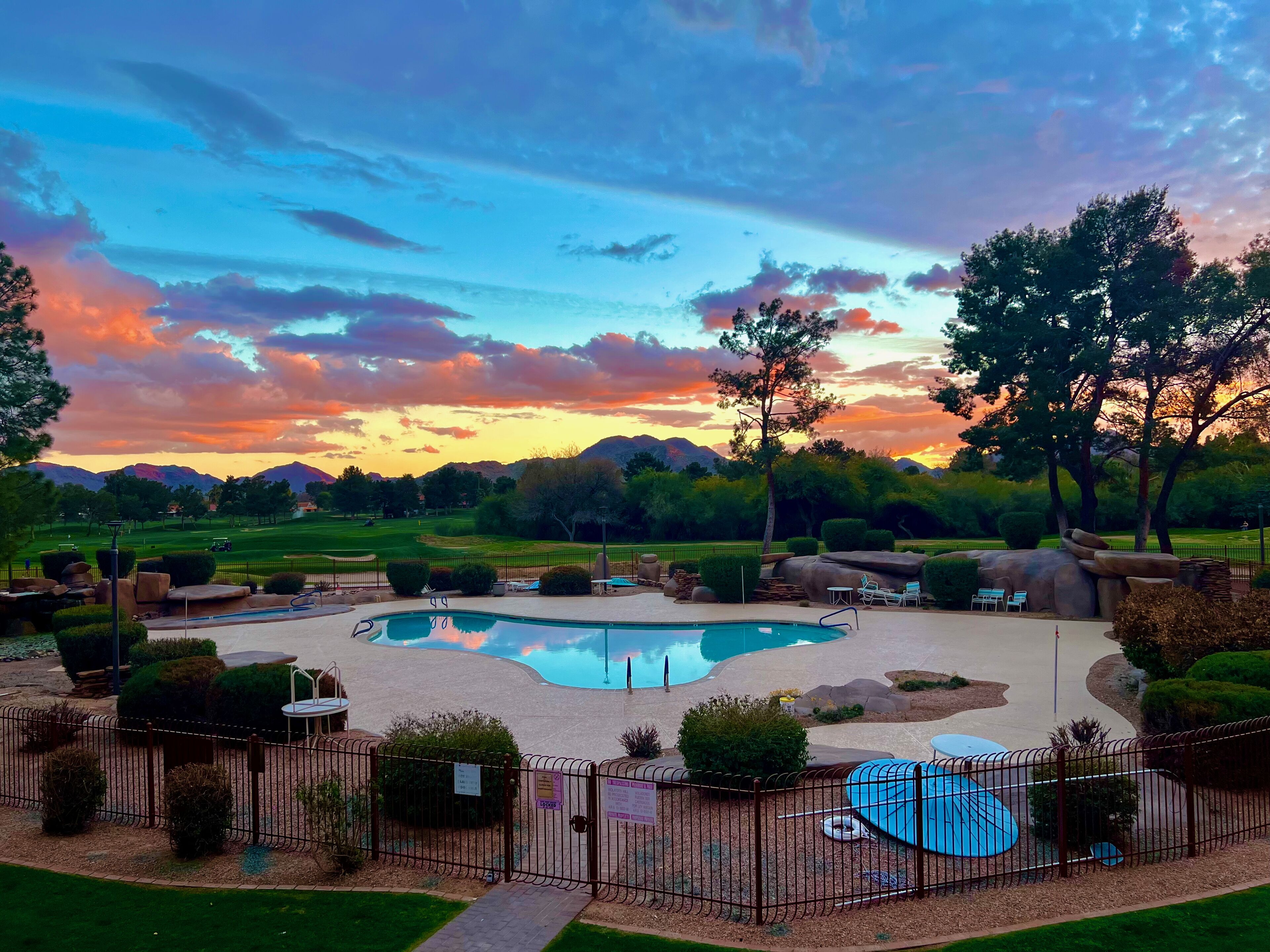 A pool area with a view of mountains and a sunset.