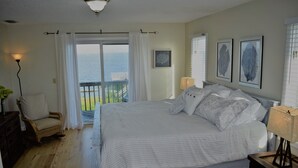 A bedroom with a large bed, a chair, a lamp, and a view of the sea. - SOUND FRONT!, Kite-In/Out! Sunsets! Dock!  (Salvo)