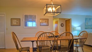 A dining area with a wooden table and chairs, framed artwork on the walls, and a chandelier. - SOUND FRONT!, Kite-In/Out! Sunsets! Dock!  (Salvo)
