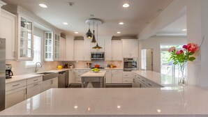 Una cocina moderna con armarios blancos, una isla central e iluminación colgante.