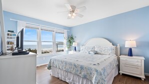 A bedroom with a bed, nightstands, a desk, and a view of the ocean. - "Oceans Edge" - Luxury Oceanfront home, 4 Bedrooms / 2.5 Bathrooms (Holden Beach)