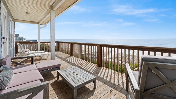 A wooden deck with lounge chairs and a table, overlooking a beach. - "Oceans Edge" - Luxury Oceanfront home, 4 Bedrooms / 2.5 Bathrooms (Holden Beach)