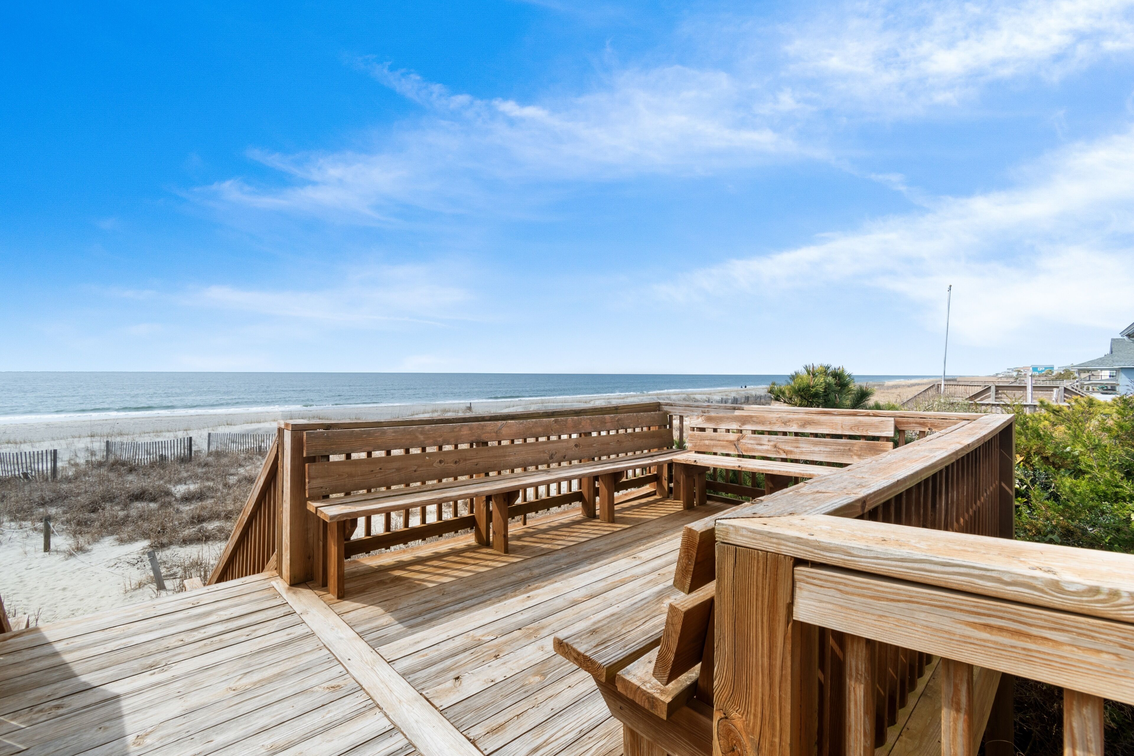 A wooden deck with benches overlooking a beach.
