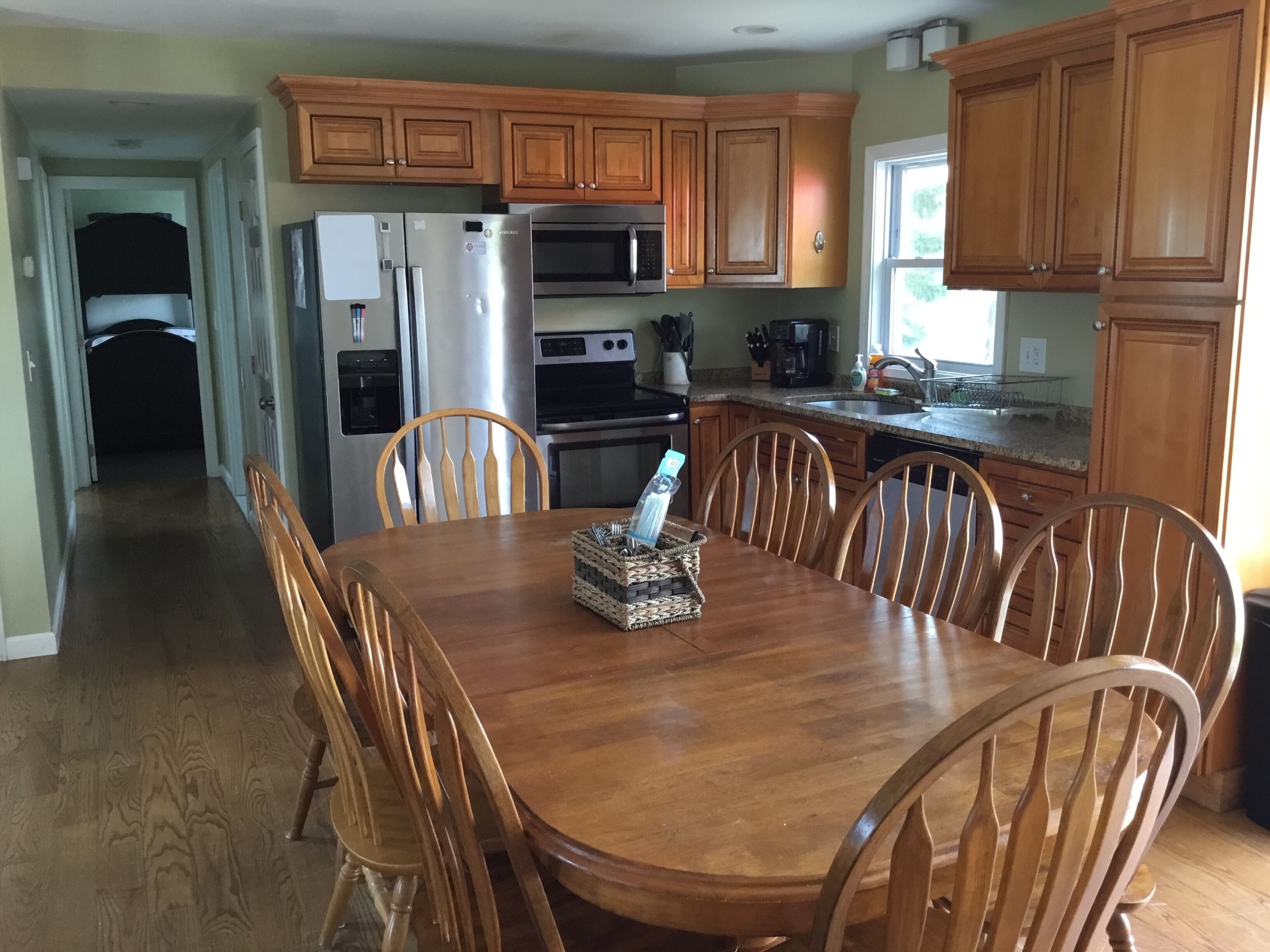 A kitchen with wooden cabinets, a stainless steel refrigerator, a microwave, and a dining table with chairs.