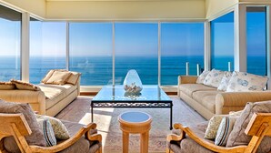 A spacious living area with a large view of the ocean, furnished with two sofas and a coffee table. - Oceanfront Beach, Pool, Hot Tub, Pickleball, Movie Theater, Elevator & Golf Cart (La Jolla)