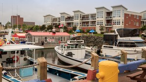 A marina with boats docked, a building with balconies, and a flag. -  Walk to Fine Restaurants & Confederation Centre of The Arts. (Charlottetown)