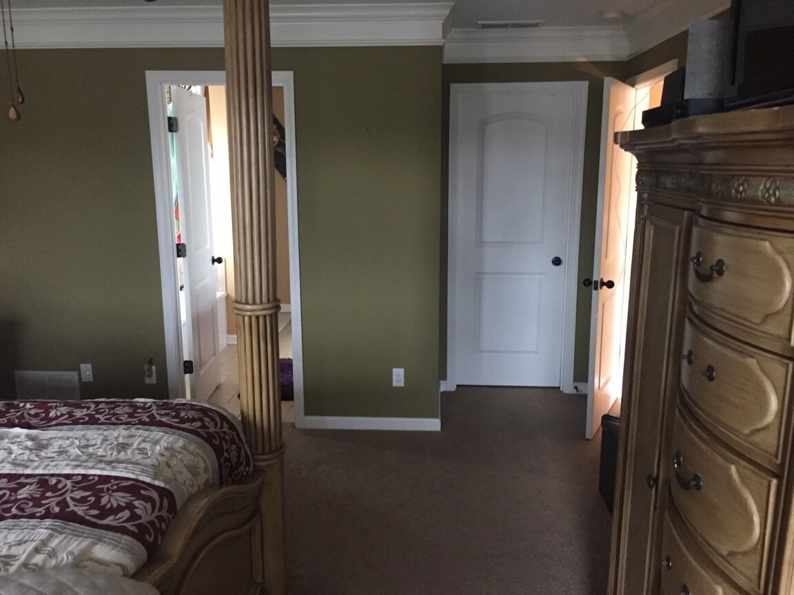 Une chambre à coucher comprenant un lit, une commode et une porte donnant sur une autre pièce.