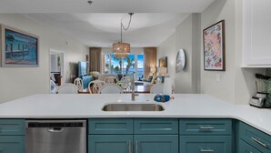 A modern kitchen with teal cabinets, a stainless steel dishwasher, and a large island with a sink. - Sumer dates are open! OCEAN FRONT & beautiful ocean view! Reduced rates! (Miramar Beach)