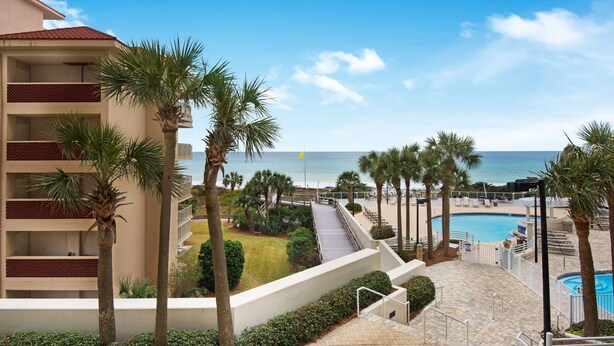 A resort with a pool, palm trees, and a view of the ocean. - Sumer dates are open! OCEAN FRONT & beautiful ocean view! Reduced rates! (Miramar Beach)