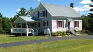 A two-story house with a porch and a small detached garage. - Beautiful Farmhouse located on 1200 acres of private bliss with a quiet pond. (Brownfield)