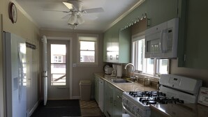 A kitchen with a gas stove, microwave, sink, and cabinets. - Beautiful Farmhouse located on 1200 acres of private bliss with a quiet pond. (Brownfield)