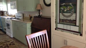 A kitchen with green cabinets, a stove, a microwave, and a clock on the wall. - Beautiful Farmhouse located on 1200 acres of private bliss with a quiet pond. (Brownfield)