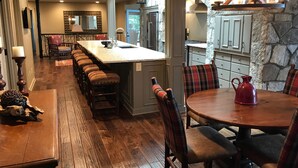 Een ruime keuken met een centraal kookeiland, houten vloeren en een eethoek met een ronde tafel en stoelen.
