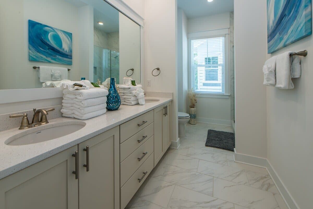 A bathroom with a large mirror, two sinks, and a toilet.