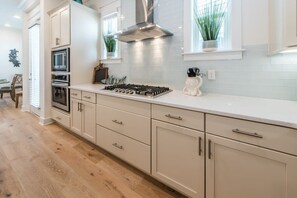 Une cuisine moderne avec des meubles blancs, des appareils en acier inoxydable et un plan de travail de couleur claire.