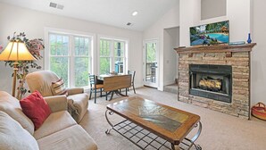 A living room with a stone fireplace, a dining table, and a sofa.