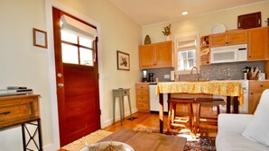A cozy kitchen with wooden cabinets, a dining table with a yellow tablecloth, and a white sofa in the living area. - In the Heart of Rosemary Beach - Beach, Pool, & Shops Steps Away (Rosemary Beach)