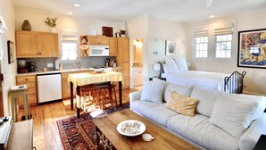 A compact living space with a kitchenette, a dining area, and a sofa with cushions. - In the Heart of Rosemary Beach - Beach, Pool, & Shops Steps Away (Rosemary Beach)