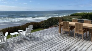 A wooden deck with a view of the ocean, a table with chairs, and a small table and chair set. - Oceanfront, Amazing View, Hot Tub Facing Ocean (Arch Cape)