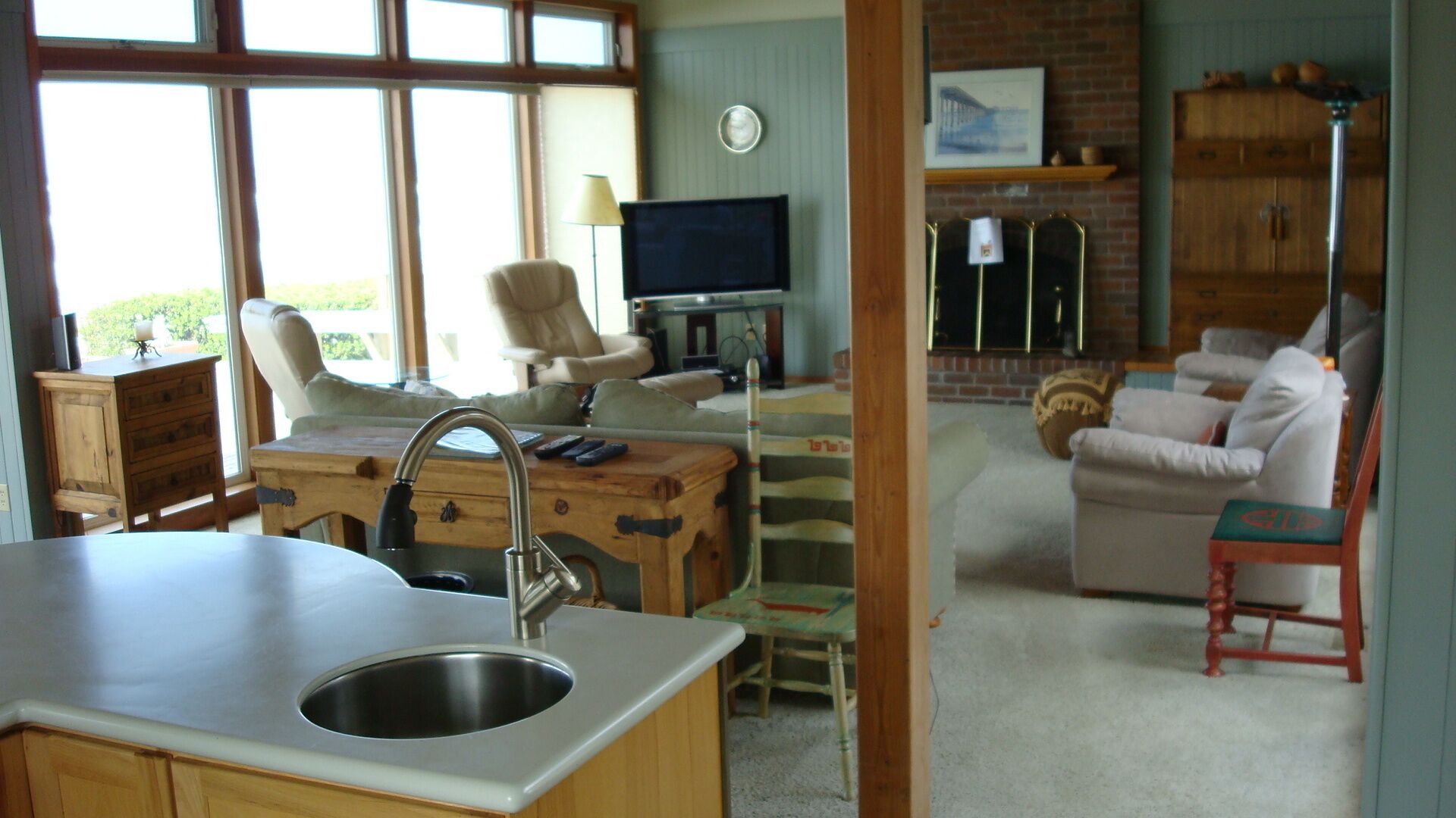 A kitchen with a sink, a dining area with a table and chairs, a television, and a fireplace.