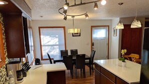 Una cocina moderna con una isla central, suelo de madera e iluminación colgante.