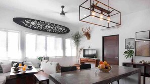 Un soggiorno moderno con zona pranzo, ampie finestre, televisore a schermo piatto e lampadario decorativo.