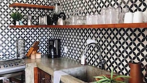 Una cucina con zanzariera decorata, mobili in legno, lavello in acciaio inossidabile e macchina per il caffè.