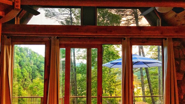 A wooden deck with a table and chairs, overlooking a forested area. - Secluded LAKEFRONT Chalet: 2.8acres, Dock, Kayaks and Canoe, Pet Friendly, Wifi (Butler)